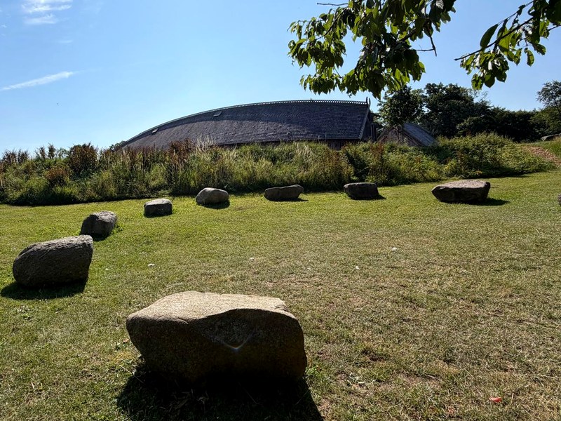 The stone circle of the assembly in the grass before the reconstructed Viking great hall at Lejre